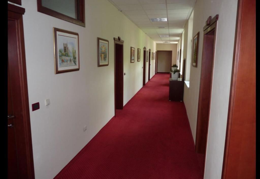 Quiet hotel corridor with red carpet and framed paintings